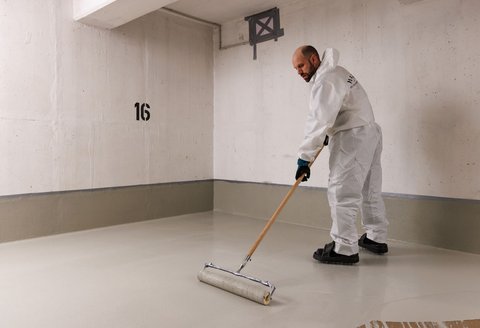 ISOTEC Mitarbeiter verteilt helle Masse auf Kellerboden