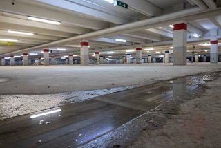Nasse Bodenfläche mit Pfütze in leerem Parkhaus, Nahaufnahme
